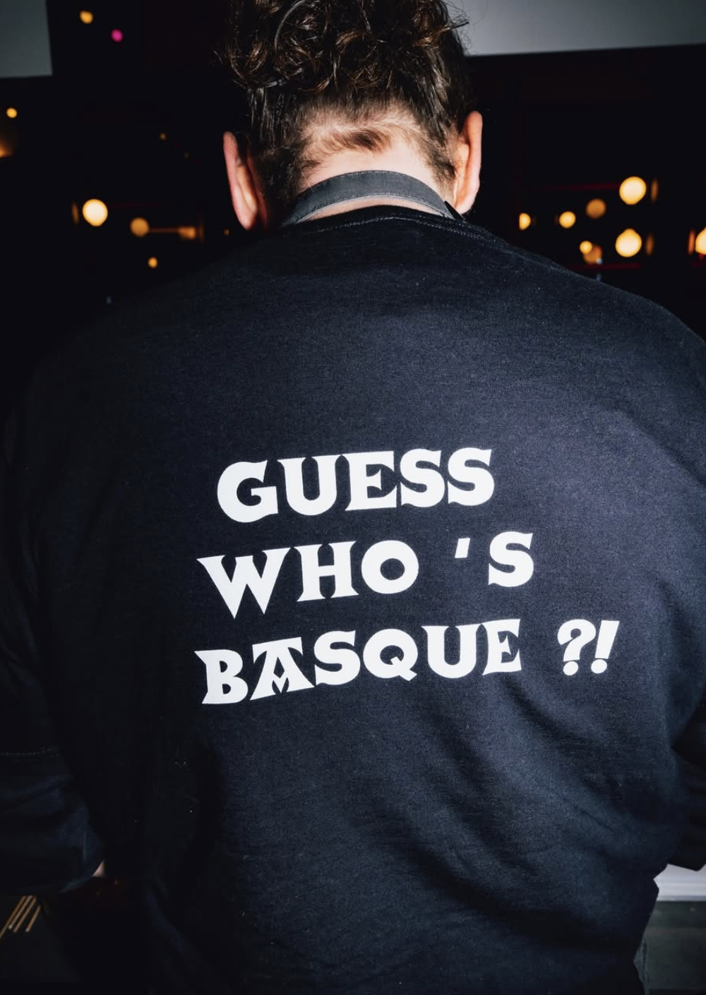 A Bask Street Boys team member wearing a 'Guess Who's Basque?!' sweatshirt at a venue event